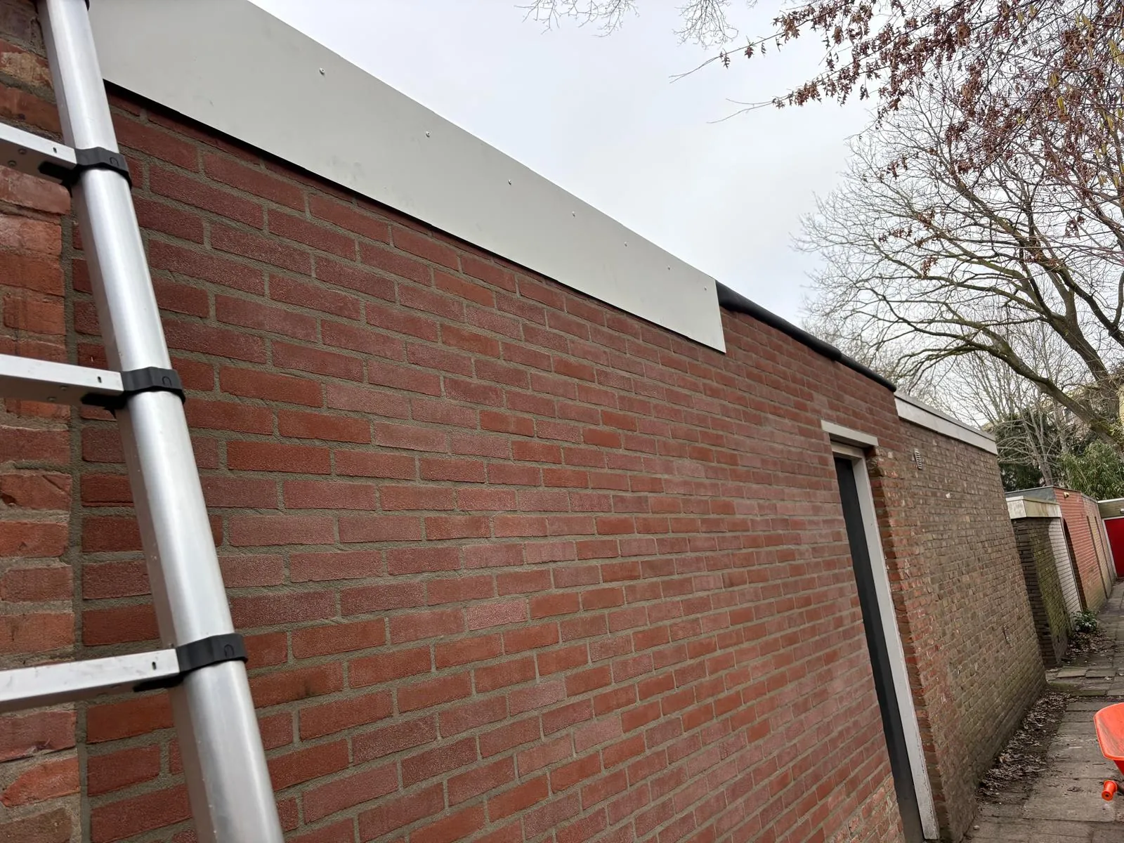 Nieuwe dakrandafwerking langs een gemetselde gevel, in één rechte lijn aangebracht